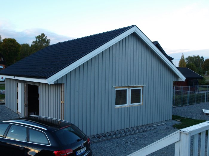 Nyligen målat hus med grå fasad och mörkt tak, med en gavel klar och en bil framför huset.