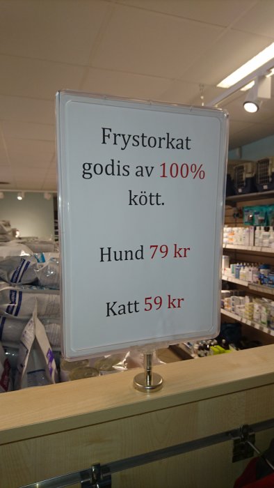 Skylt med texten "Frystorkat godis av 100% kött. Hund 79 kr Katt 59 kr" i en veterinärklinik.