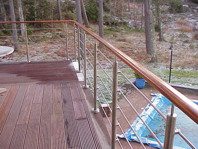 Altan med trägolv och metallräcke 2,5 meter över marken mot en skogsbakgrund.