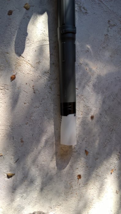 Ryobimaskin med hemmagjord förlängning på blåsrör från plastflaska, lutande mot en markyta med löv.