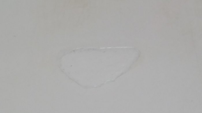 Reparerad skada på vit laminatbänkskiva med synlig lagning och glipa.