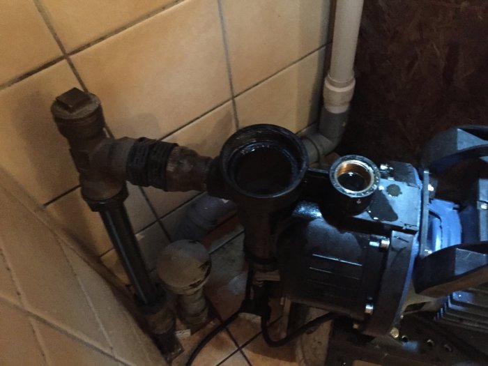 Vattenpump och filterblåsa med öppna kopplingar inuti ett utrymme.