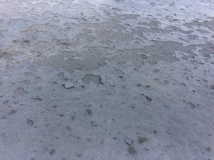 En skadad betongplatta med flagnande och fransiga ytor som uppstått vid torkning.