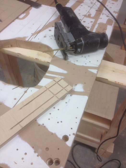 En sticksåg som skär i en plywoodbit med uppmätta snitt och träspån på arbetsbordet.
