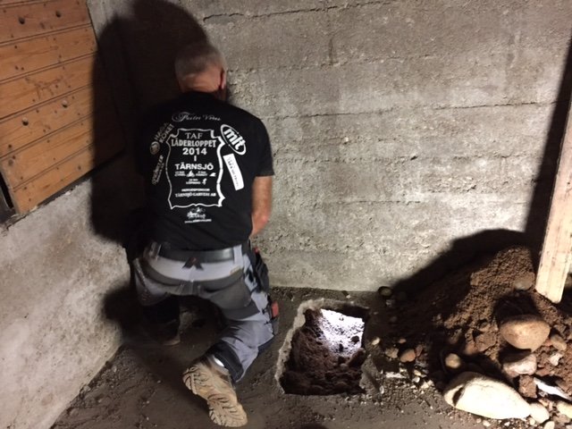 Person gräver golv i tvättstuga för installation av avlopp.