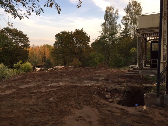 Grävarbetsplats med jord och sten framför ett hus, avslutad grävning för vatten, avlopp och fiber.