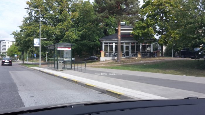 Bild från bilens perspektiv visar en gatuvy med HamburgarPrinsen grillkiosk och en busshållplats.