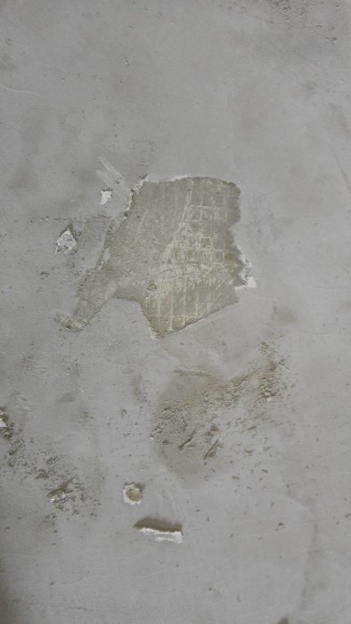 Betong med rester av avskrapat skikt och fuktfläckar från renoveringsprojekt.