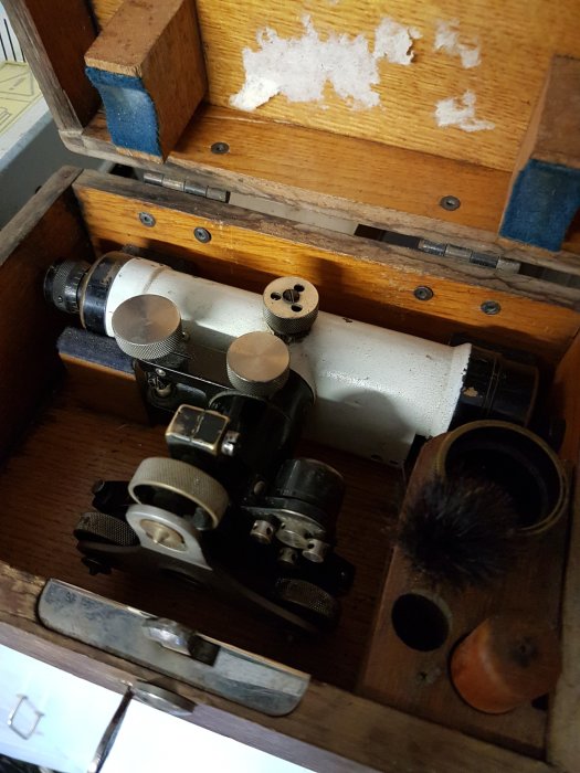 Gamla instrument och verktyg i en träväska, möjligen för teknisk eller vetenskaplig användning. Slitet utseende och historiskt intresse.