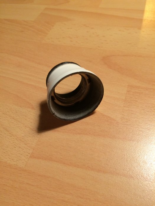 Lampdel på träyta för glödlampsfäste med svart och vit ring.