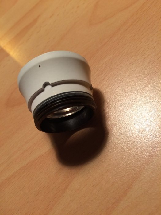 En lampa fattning avsedd för glödlampor ligger på ett träbord, sedd uppifrån.