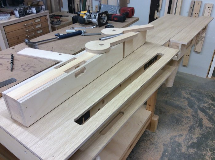 Arbetsbänksdelar i björkplywood med ursparningar och excentrar på en verkstadsbänk, verktyg i bakgrunden.