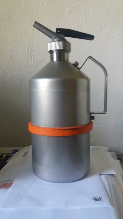 Metallic cylinder with a handle, sil, valve on top, and an orange band, queried for its unknown use and structure.