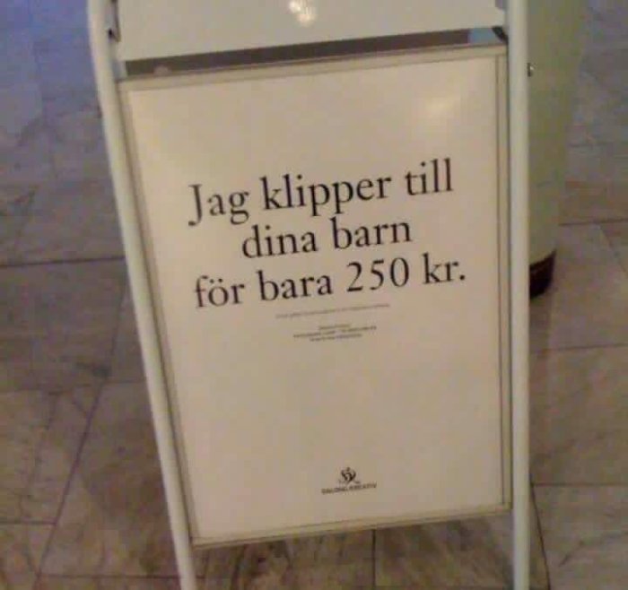 Skylt med texten "Jag klipper till dina barn för bara 250 kr." på ett gångvägsställ.