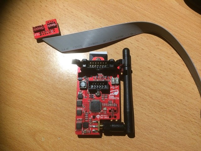 Robonect Hx-kort med antenn och flatkabel bredvid en adapter på träbord.
