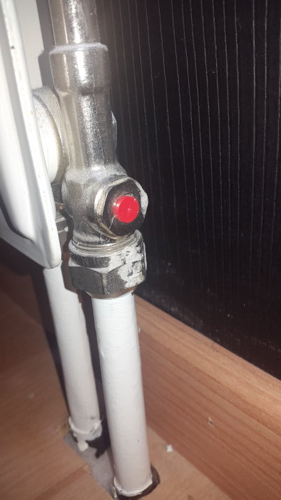 Närbild av en radiatorventil utan synlig avstängningsmekanism vid en svart radiator.