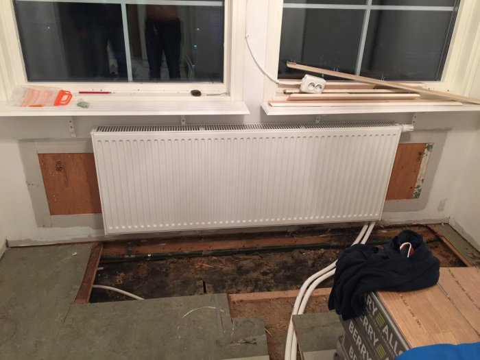 Nyinstallerat radiator i renoveringsprojekt med synliga PEX-rör och avlägsnat golv.