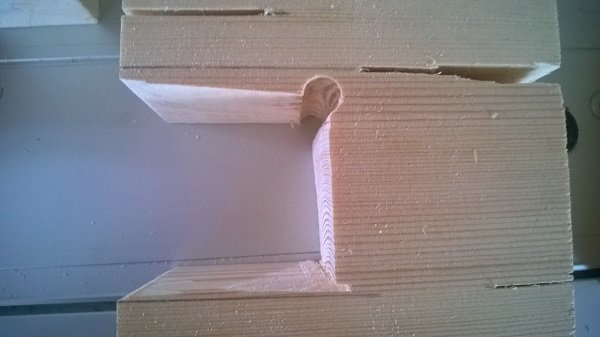 Grovdimensionerad träkarm med ojämn och sned sågad slits, illustrerar problem vid tillverkning av stallfönster.