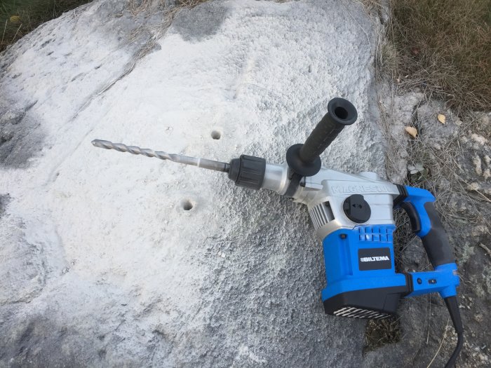 Elektrisk borr från Biltema används för att borra 18mm hål i betong, med synliga borrspår och gräs i bakgrunden.