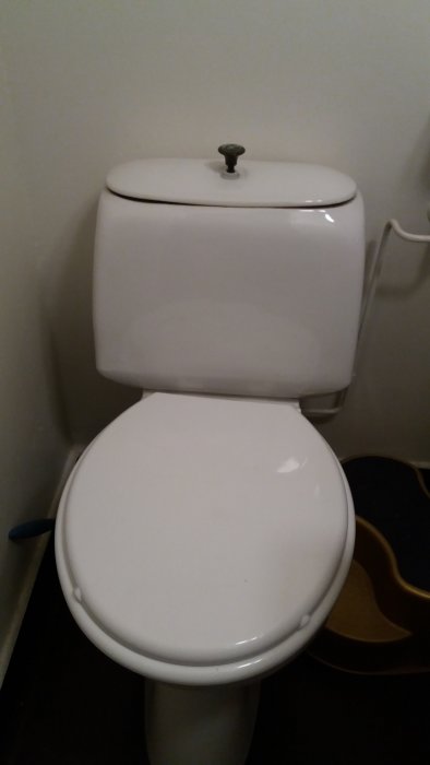 Stängd vit toalettstol i ett badrum, vilket indikerar att den inte läcker vatten.