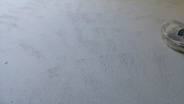 En slipad betongplatta med synliga ojämnheter och del av en slipmaskin i förgrunden.