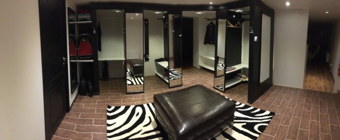 Renoverad klädkammare med svartmålade spegeldörrar, inbyggda hyllor och zebra-mönstrad matta.