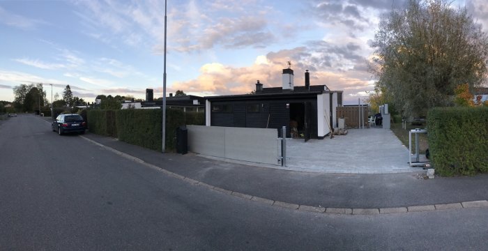 Panoramavy över ett hus med nyinstallerad fibercementgrind och garage i skymningsljus.