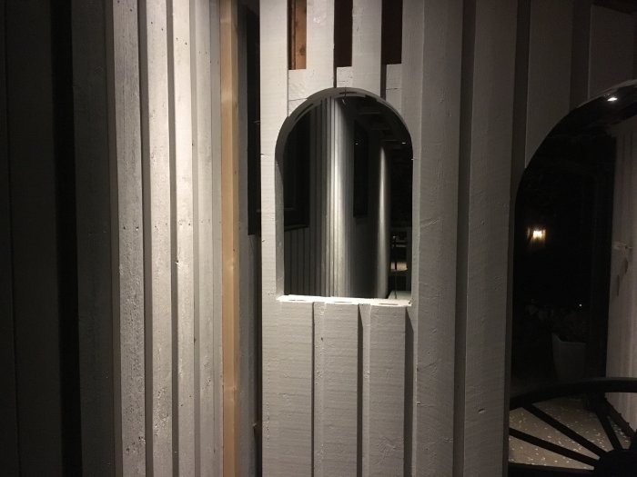 Yttervägg med nyinstallerad belysning vid ett fönster på en träfasad under kvällstid.