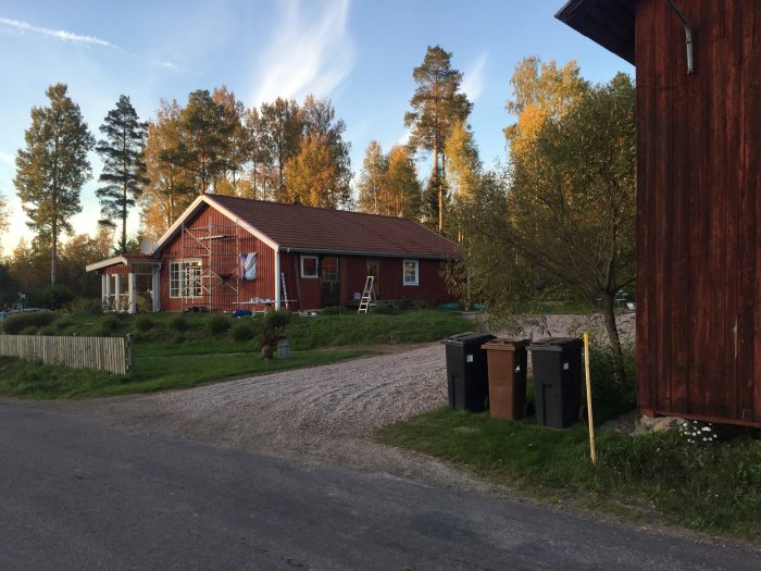 Två röda hus i olika nyanser under renovering, en med stege och omonterade vita fönsterspröjs.