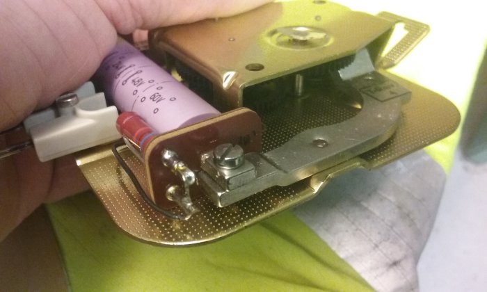 Inre mekanism av en klocka med synlig trådrulle och elektroniska komponenter, ej ett traditionellt urverk.
