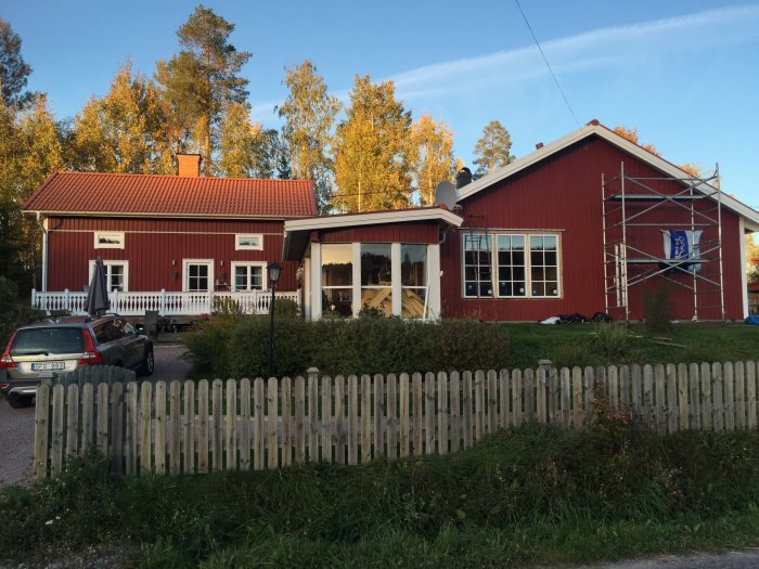 Falurött hus under renovering med byggnadsställning och icke-monterade spröjs och foder vid ytterdörren.