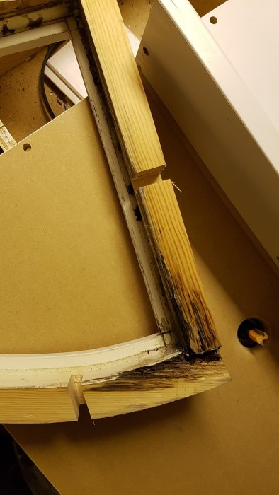 Del av ett fönsterbåge under renovering visar byte av ruttet trä mot frisk furu, bredvid hyvel och arbetsbänk.