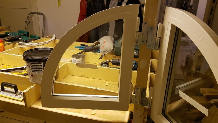 Renoverade fönsterbågar i verkstad med verktyg och råmaterial synliga i bakgrunden.