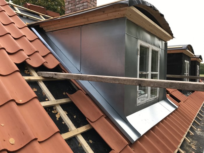 Plåtslagning på takfot och hörn av hus med nyinstallerad plåt och omlagt tegeltak.