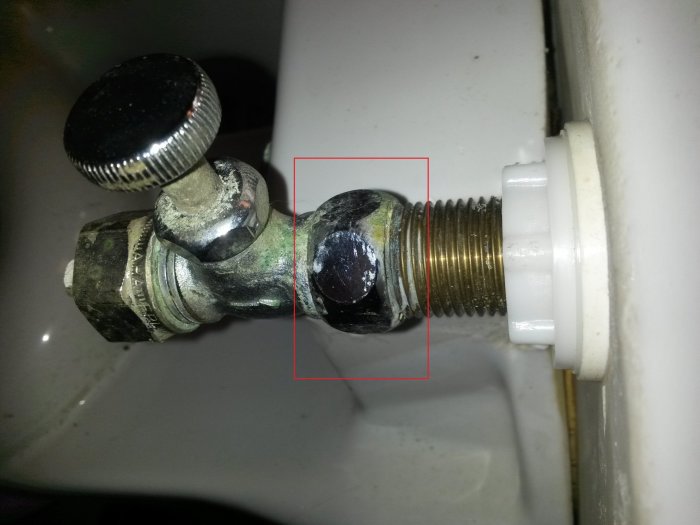 Närbild av gammal vattenrörsanslutning med mutter och rörstump mot en vägg.