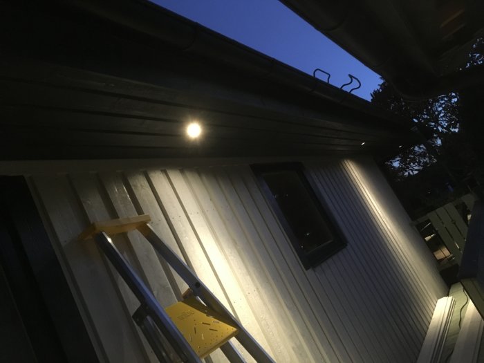 Nyinstallerad takfot på hus med stege i skymningen och lykta som lyser.