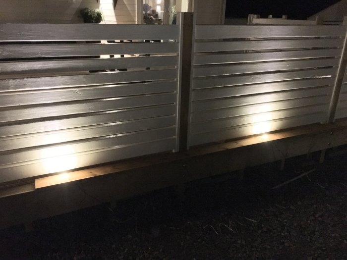 Altanräcke med decklights placerade både framför stolpar och mellan stolparna på kvällstid.