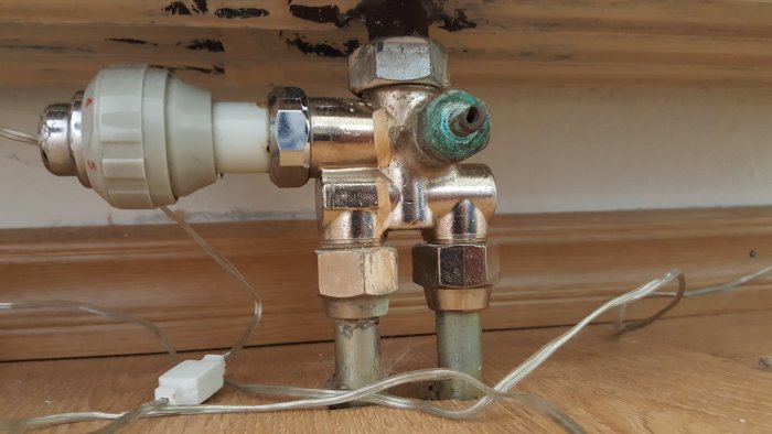 Elementventil där vredet saknas, kopparledningar och termoelement mot en trävägg.