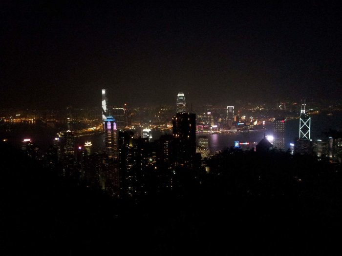 Nattvy över Hong Kongs upplysta skyline och Victoria Harbour tagen från ett högre perspektiv.