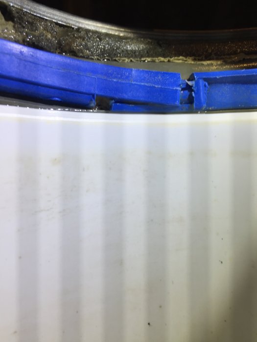 Vit duschvägg med randiga skuggor från LED-lampa och tejpade kanter längst upp på väggen.