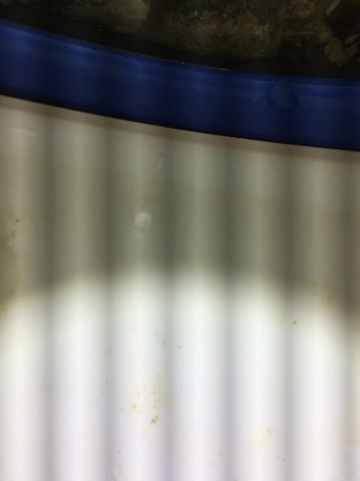 Närbild på en dusch med ränder skapade av LED-ljus och synliga vattendroppar och smutspartiklar.
