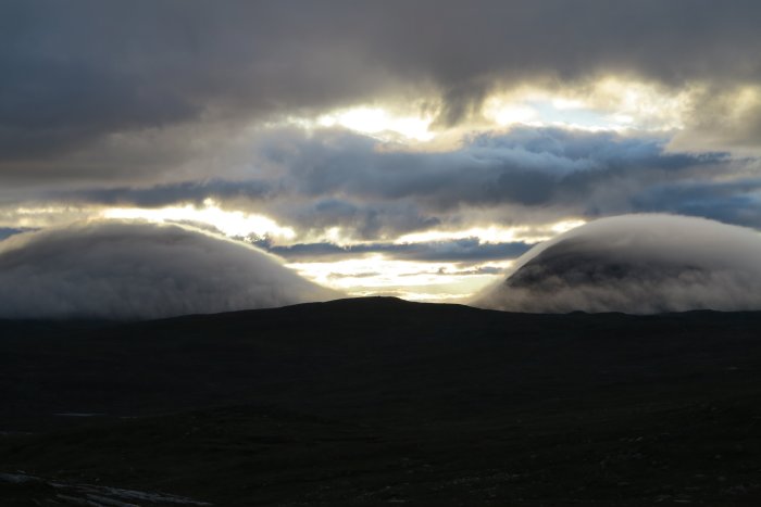 Molntäckta bergstoppar i Jämtland med dramatisk himmel vid solnedgång.
