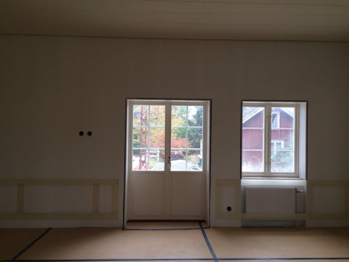 Rum med blivande spegelpaneler upp till fönsterbänkshöjd, elementskydd och markerade ytor med tejp.