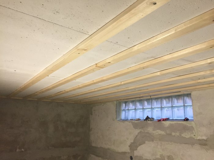 Nyinstallerad glespanel och innertak av Huntonit i en källartvättstuga, oavslutad med förberedelse för spotlights.