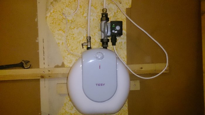 Elektrisk värmare installerad på en vägg med floral tapet för att tillfälligt värma upp badrum.