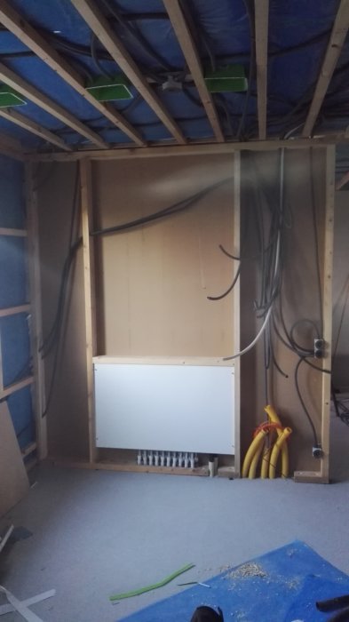 Installation av golvvärme med synliga rör och elslangar i ett rum under renovering.