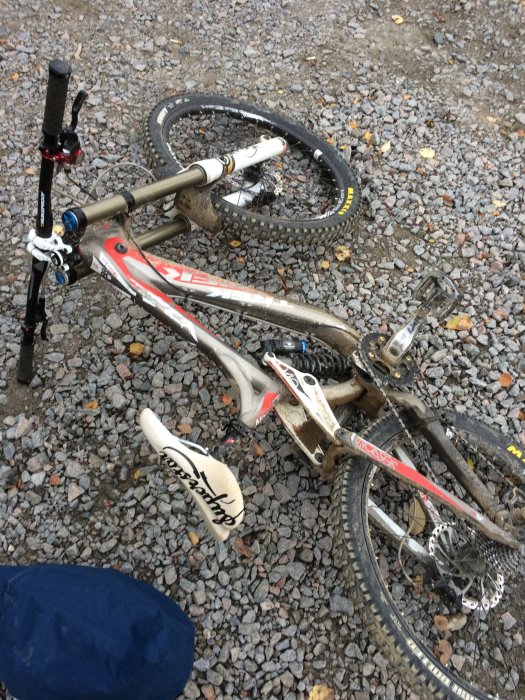 Nedsmutsad mountainbike ligger på grus efter en tur i Järvsö bergscykelpark.