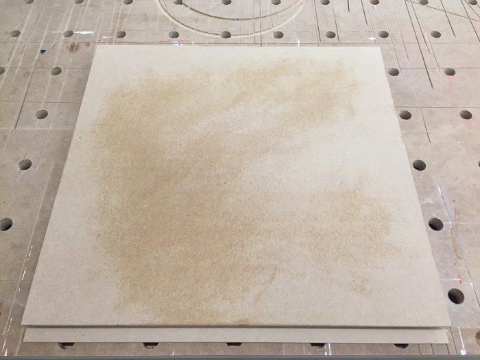 MDF-skiva med slipade sidor och fingergrepp, förberedd för grundmålning, på en arbetsbänk med hål.