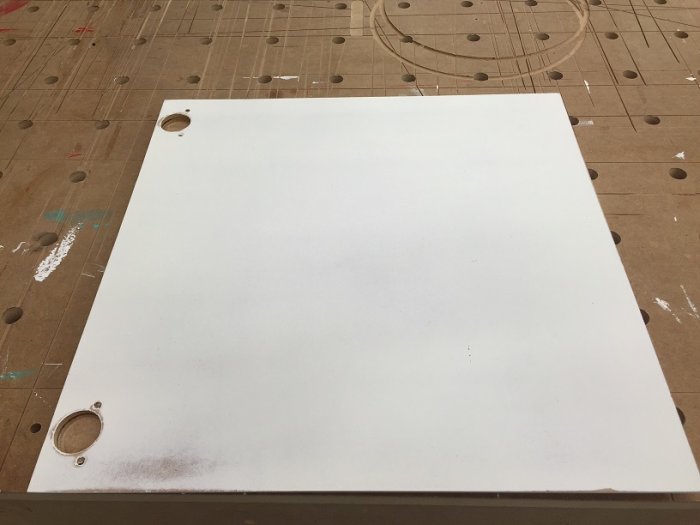 MDF-skåpsfront med frästa fingerfästen och delvis grundmålad yta på arbetsbord.