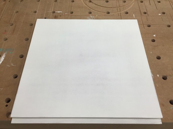 Grundmålad MDF-skåpsfront på verkstadsbord, redo för vidare målning och montering.